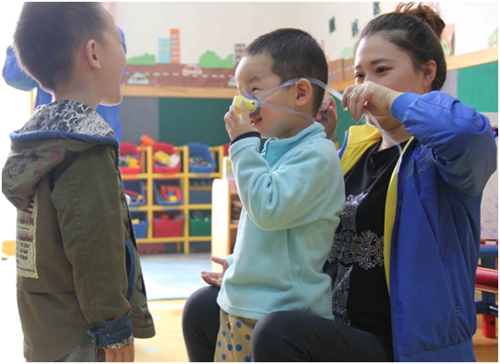 幼儿园老师帮助孩子佩戴防雾霾鼻罩 